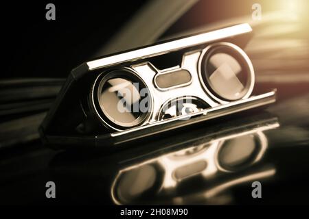 Closeup vintage folding opera glasses. Old compact binoculars. Stock Photo