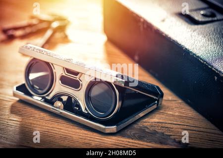 Closeup vintage folding opera glasses. Old compact binoculars. Stock Photo