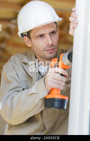 man drilling a hole in a window frame Stock Photo