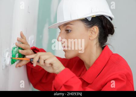 female electrician testing a wall socket Stock Photo