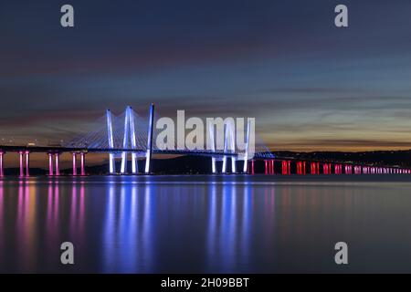 The Governor Mario M. Cuomo Bridge, illuminated in red, white, and blue in recognition of Columbus Day, spans the Hudson River just after sunset. Stock Photo