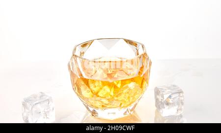 Glass of whiskey with ice cubes on white background with reflection Stock Photo