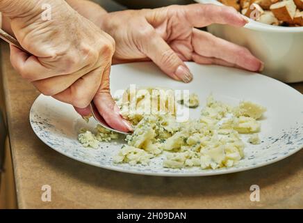 With a fork, the chef kneads mashed potatoes on plate Stock Photo