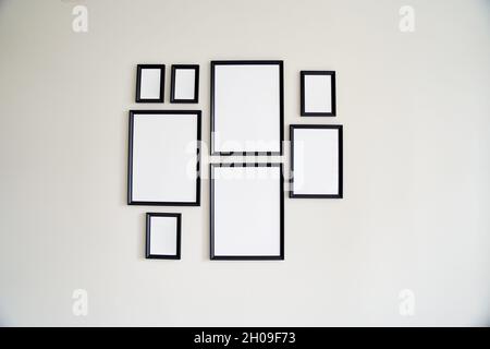Different size framed photos hanging on the gray wall. Mockup. Stock Photo