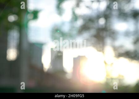 Blur city and trees with lens flare during sunset. Business or urban background concept. Stock Photo