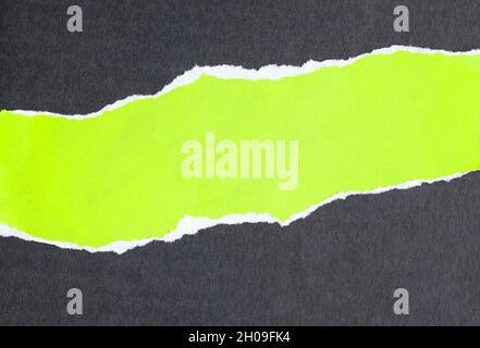 Ripped fluorescent green paper on black background. Copy for advertising space. Stock Photo