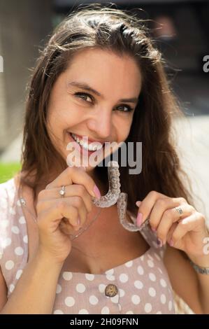 Beautiful caucasian woman holding transparent mouth guards for bite correction. Stock Photo