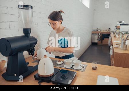 Nice female barista making coffee in cafeteria Stock Photo