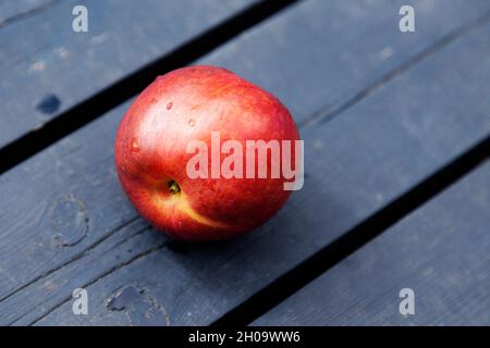 a nectarine lying on a blue cutting board Stock Photo