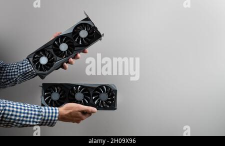 Cropped view of man holding two video cards on gray background. Bitcoin cloud mining Stock Photo