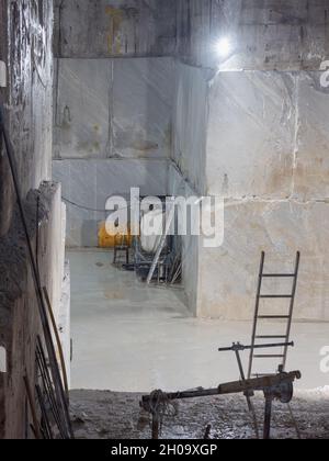 Marble Quarry with a ladder and other working tools inside the Mountain in Carrara, Tuscany - Italy. Stock Photo