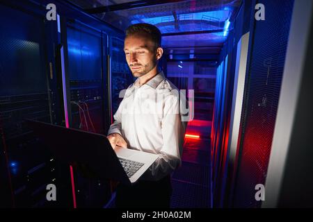 System technician running diagnostic of server racks with laptop Stock Photo