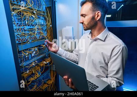 Male IT engineer connecting cable to server rack Stock Photo