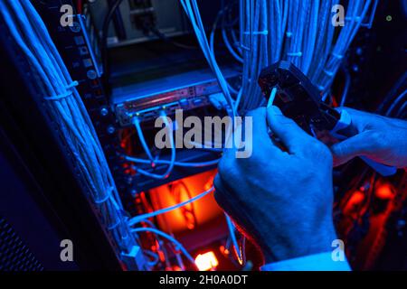 Server technician putting UTP cable into crimping pliers Stock Photo