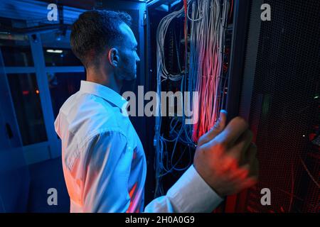 Man inspecting cables and wires of network equipment Stock Photo
