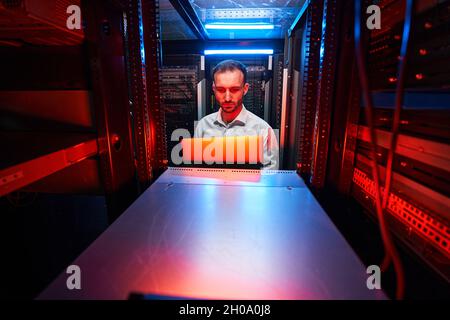 Technician with laptop in front of server rack Stock Photo