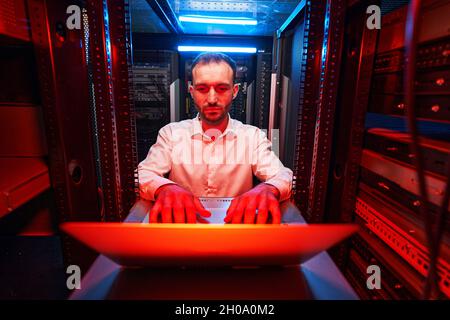 Data center operations specialist typing on laptop keyboard Stock Photo