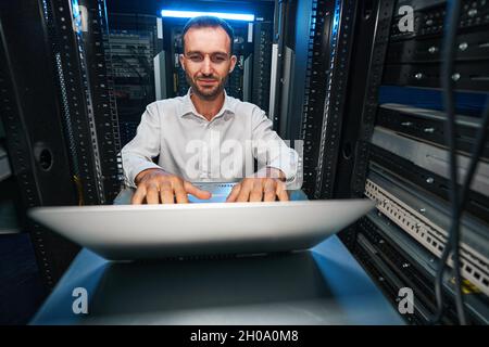 Satisfied data center manager checking network settings with laptop Stock Photo