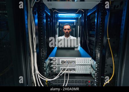 Male network administrator running software check of server equioment Stock Photo