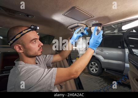 Professional service worker cleaning vehicle interior in automobile repair shop Stock Photo