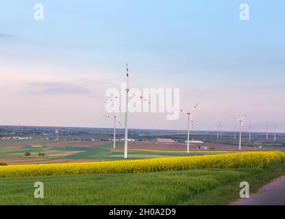 Wind turbine farm in yellow rapeseed fields in spring time. Renewable energy sources concept Stock Photo