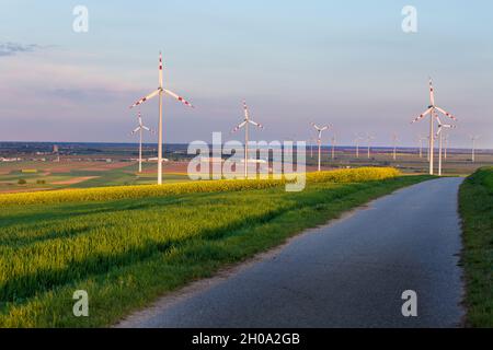 Wind turbine farm in yellow rapeseed fields in spring time. Renewable energy sources concept Stock Photo