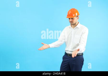 Businessman builder in misunderstanding on blue background. Stock Photo