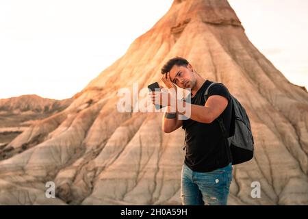 Young caucasian man using a smartphone while visiting Bardenas Reales desert in Navarra, Basque Country. Stock Photo