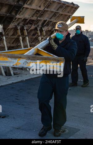 210109-N-OB471-1167 NORFOLK, Va. (Jan. 9, 2021) Airman Alex Smith, from Long Island, New York, carries a stanchion aboard the Nimitz-class aircraft carrier USS Dwight D. Eisenhower (CVN 69). Ike is currently pier side in Naval Station Norfolk conducting routine maintenance. Stock Photo