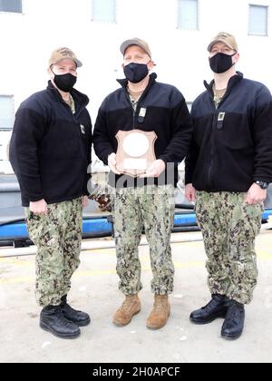 210113-N-AY795-017 GROTON, Conn. (January 12, 2021) – Capt. Matthew Boland, commander of Submarine Squadron (SUBRON) TWELVE, center, presents the Battle “E” award to the crew of the USS Newport News (SSN 750), represented by Cmdr. David Fassel, commanding officer, left, and Master Chief Petty Officer Dean Marvin, chief of the boat, right, on board naval Submarine Base New London in Groton, Conn., Jan. 13. The Battle “E” competition recognizes commands that attained the highest overall or departmental readiness to carry out its assigned wartime tasks as a unit of the Atlantic Submarine Force, a Stock Photo