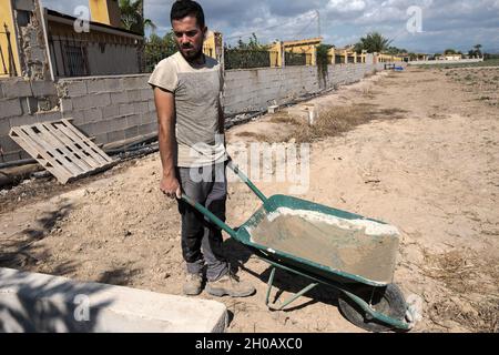 Young worker transporting materials with a wheelbarrow. Effort concept. Stock Photo