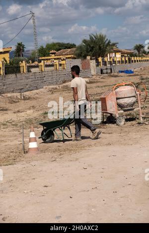 Young worker transporting materials with a wheelbarrow. Effort concept. Stock Photo