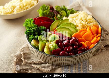 From above of delicious Buddha bowl with fresh assorted vegetables and couscous served on napkin on table Stock Photo