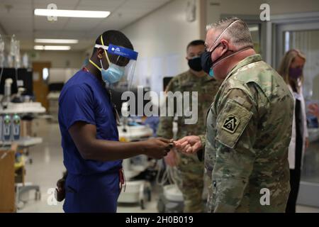 U.S. Army Maj. Gen. John F. King, commander of Task Force 51, presents U.S. Air Force Staff Sgt. Andre Petway a commander’s coin for his continued hard work in his deployment to Riverside University Healthcare System in Riverside Calif., Jan. 14, 2021. U.S. Northern Command, through U.S. Army North, remains committed to providing flexible Department of Defense support to the whole-of-government COVID-19 response. Stock Photo