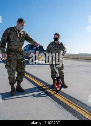 Senior Airman Kristina Grafton, 436th Operation Support Squadron airfield management operations supervisor and Senior Airman Keyton Nickell, 436th Airfield Operation Support Squadron airfield management shift lead, measure a center taxi line on the runway at Dover Air Force Base, Delaware, Jan. 14, 2021. As airfield management journeymen, Grafton and Nickell manage airfield operations, coordinate with civil engineers, safety, air traffic control and various other base agencies to ensure safe aircraft operations within the airfield of Dover AFB. Stock Photo