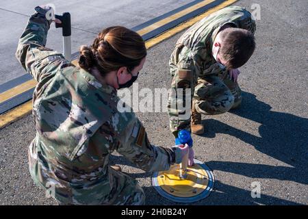 Senior Airman Kristina Grafton, 436th Operation Support Squadron airfield operations supervisor, and Senior Airman Keyton Nickell, 436th Airfield Operation Support Squadron airfield management shift lead, inspect a taxiway edge light at Dover Air Force Base, Delaware, Jan. 14, 2021. As  airfield management journeymen, Grafton and Nickell manage airfield operations, coordinate with civil engineers, safety, air traffic control and various other base agencies to ensure safe aircraft operations within the airfield of Dover AFB. Stock Photo