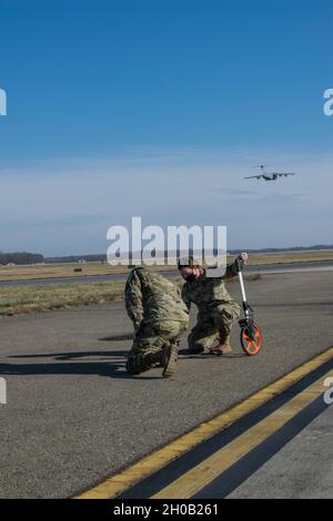 Senior Airman Kristina Grafton, 436th Operations Support Squadron airfield operations supervisor, and Senior Airman Keyton Nickell, 436th Airfield Operation Support Squadron airfield management shift lead, inspect a taxiway edge light at Dover Air Force Base, Delaware, Jan. 14, 2021. Airfield management conducts hourly runway inspections to ensure military, civilian, and foreign military aircraft can arrive and depart safely. Duties of the career also consist of coordinating with civil engineers, safety, air traffic control and various other base agencies to ensure safe aircraft operations wit Stock Photo