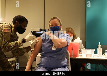 Spc. Anthony Shepherd, a medic assigned to the 224th Medical Company Area Support, Maryland Army National Guard, administers a COVID-19 vaccine Jan. 18, 2021, at Anne Arundel Community College in Arnold, Md. Maryland Guard members are supporting the COVID-19 vaccination initiative with mobile vaccination support teams, which are providing medical and logistical support to county health departments during the global COVID-19 pandemic. Stock Photo