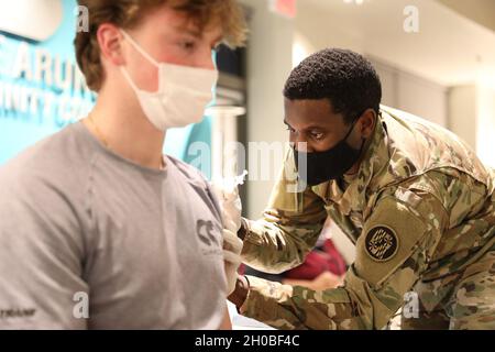 Spc. Anthony Shepherd, a medic assigned to the 224th Medical Company Area Support, Maryland Army National Guard, administers a COVID-19 vaccine Jan. 18, 2021 at Anne Arundel Community College in Arnold, Md. Maryland Guard members are supporting the COVID-19 vaccination initiative with mobile vaccination support teams, which are providing medical and logistical support to county health departments during the global COVID-19 pandemic. Stock Photo