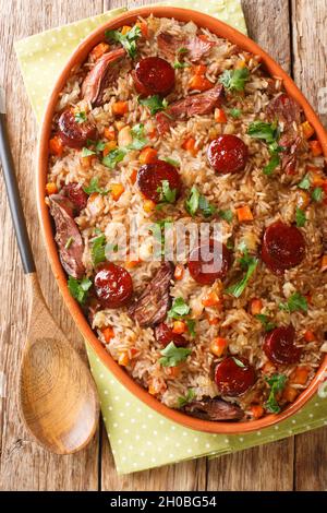 Arroz de pato or duck rice is a traditional Portuguese food close up in the baking dish on the wooden table. Vertical top view from above Stock Photo