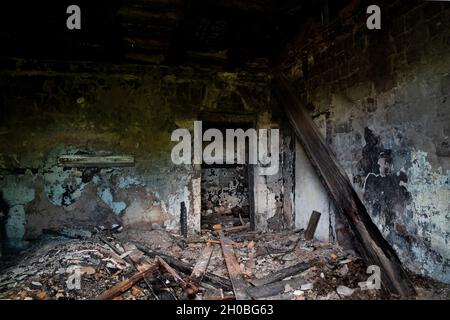 An abandoned building to be demolished, with sooty walls and a collapsed plank ceiling, after a fire. Stock Photo