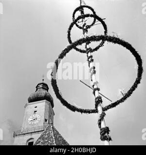 Ein Gemeindemaibaum wird in der Stadt Cham gesetzt, in unmittelbarer Nähe zur Stadtpfarrkirche, Deutschland 1930er Jahre. A traditional maipole is set near the Stadtpfarrkirche church at Cham, Germany 1930s. Stock Photo