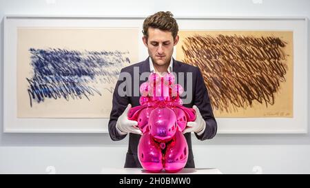 London, UK. 12th Oct, 2021. Gallery staff with 'Dom Perignon Balloon Venus', by Jeff Coons (2013) and Cy Twombly work on the walls. Jeff Koons & Cy Twombly: Primal Gestures opens at Bastian Gallery in Mayfair, an exhibition which brings together a highly unusual pairing of two giants of post-war art. Highlighting two seemingly opposing practices, the exhibition exposes Twombly's rich visual lexicon of mark-making and gestural abstraction, pairing it with the reductive nature of Koons' machine-made fabrications. Credit: Imageplotter/Alamy Live News Stock Photo