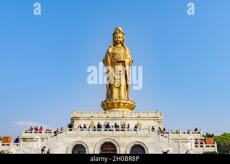 Zhejiang, China - 03 November 2017: Tourists visiting and giving prayers at golden Guan Yin Buddha statue. Stock Photo