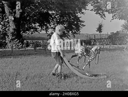 Ein Bauernjungein Westfalen spielt mit seinem Schaukelpferd, Deutschland 1930er Jahre. A farmer boy of Westphalia playing with his rocking horse, Germany 1930s. Stock Photo