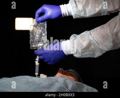 Doctor holds a dropper in his hands with medicine for a female patient in a hospital, close-up Stock Photo