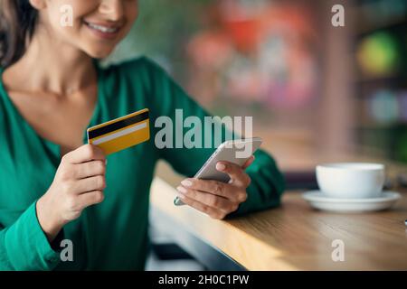 Cropped of young lady using mobile phone and credit card Stock Photo