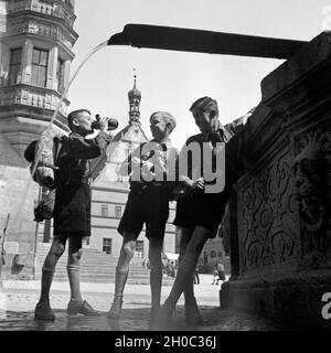 Drei Hitlerjungen füllen ihre Wasserflaschen an einem Brunnen in Rothenburg ob der Tauber auf, Deutschland 1930er Jahre. Three Hitler youths refilling their water bottles at a fountain at Rothenburg ob der Tauber, Germany 1930s. Stock Photo