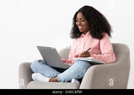 Cheerful african-american woman attending webinar, using laptop Stock Photo