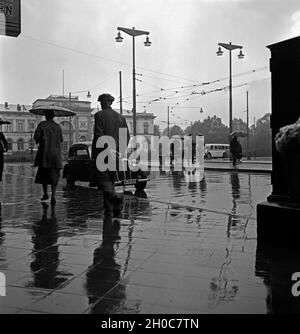 Menschen eilen im Regen auf dem Platz vor dem Hauptbahnhof in Braunschweig, Deutschland 1930er Jahre. People in a hurry on the square in front of Braunschweig main station, Germany 1930s. Stock Photo